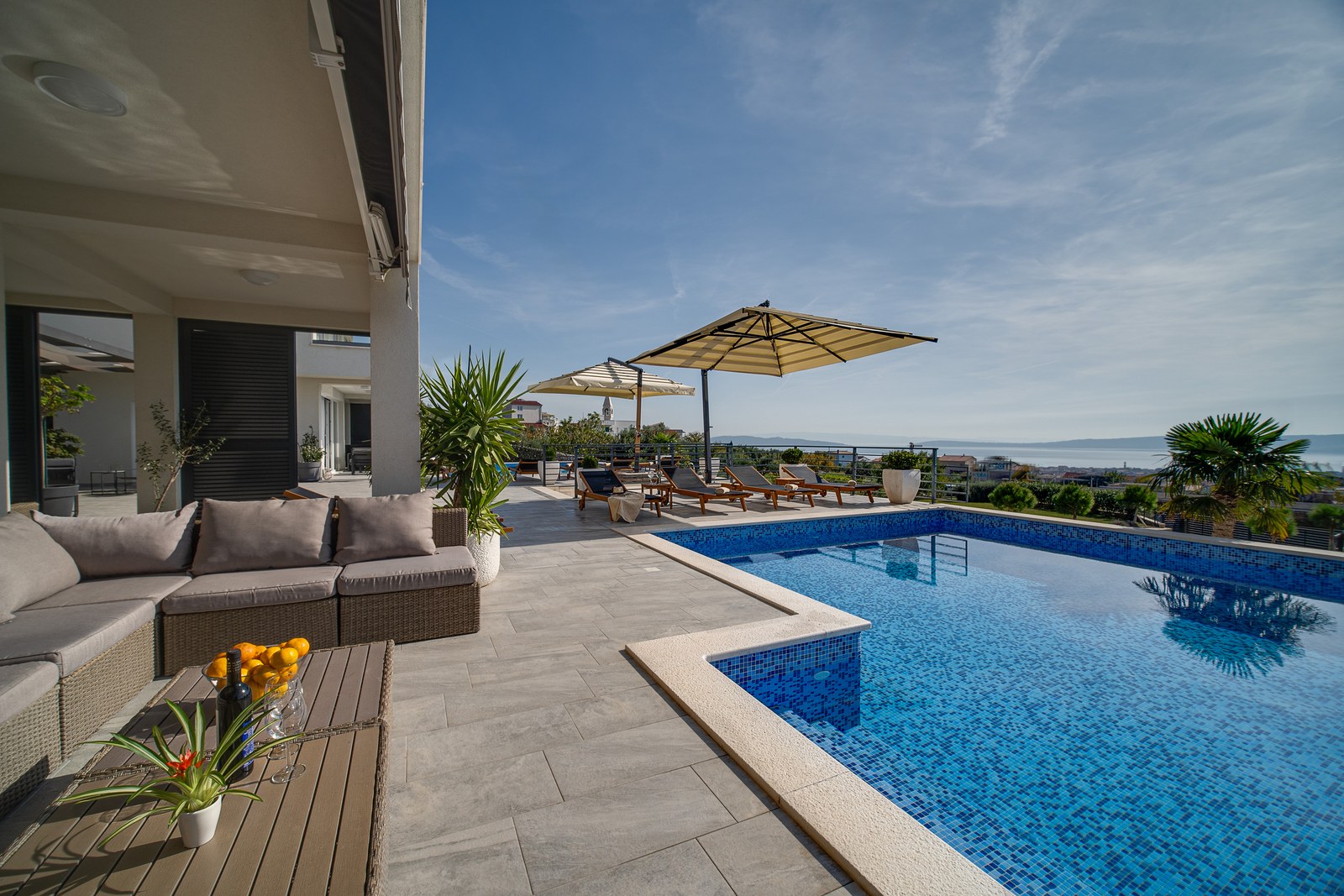Shaded lounge terrace beside a private pool with sweeping views across the Adriatic